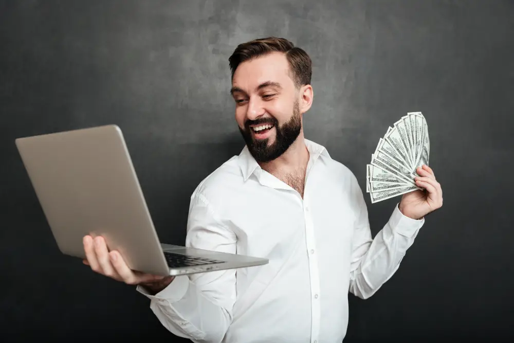 man holding laptop and money